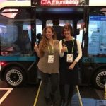Two women stand in front of accessible olli bus