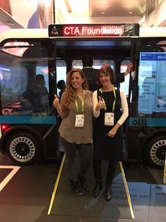 Two women stand in front of accessible olli bus