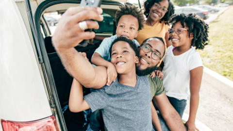 family selfie in front of car