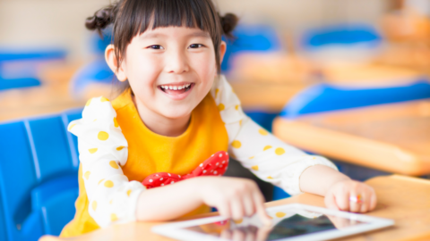 girl in orange shirt using ipad