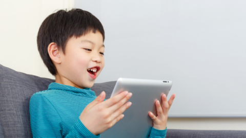 boy holding ipad on couch