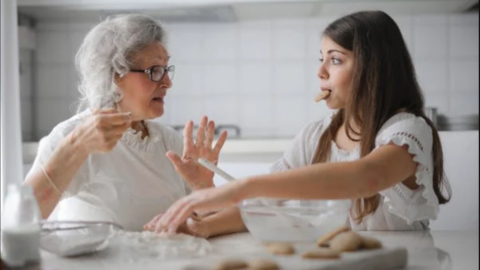 older adult female making cookies with teen girl