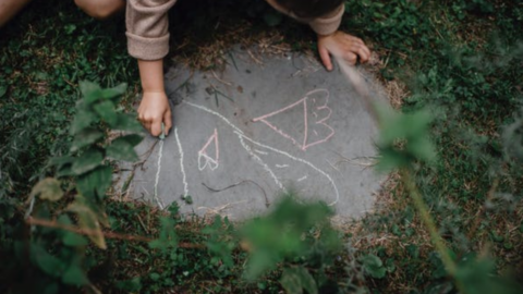 Child writing with chalk on sidewalk