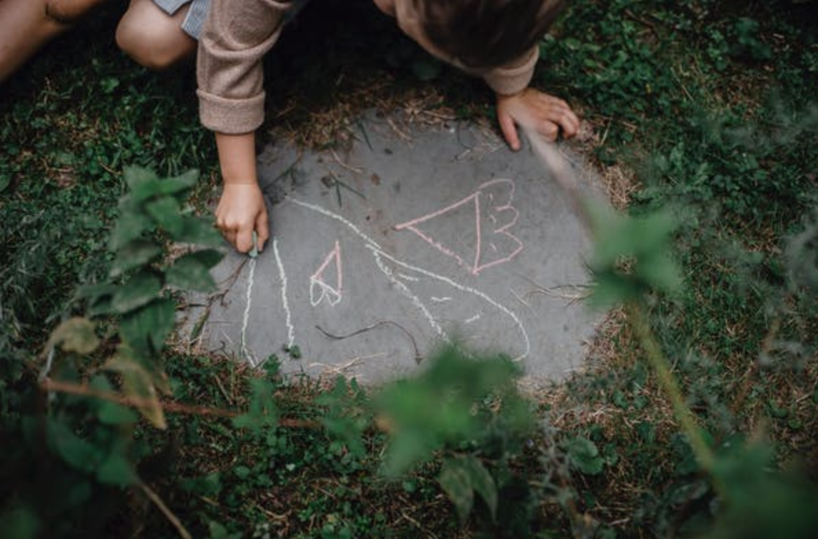 Child writing with chalk on sidewalk