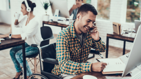 man in wheelchair working at desk in office