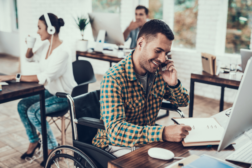 man in wheelchair working at desk in office
