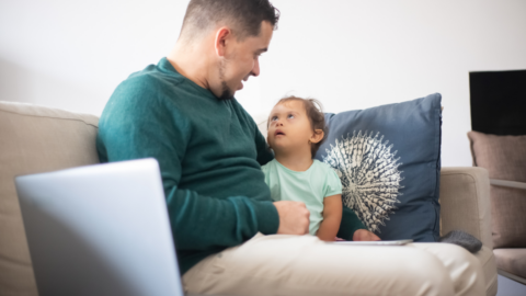 dad and toddler daughter sitting together on couch