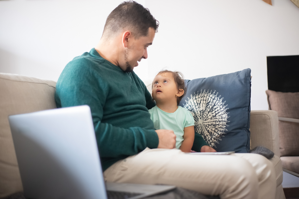 dad and toddler daughter sitting together on couch