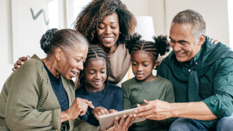 3 generation family smiling and looking at tablet device