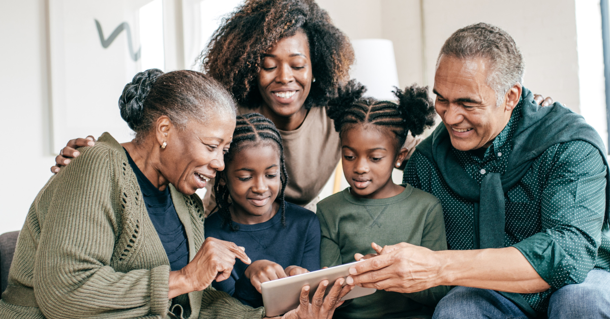 3 generation family smiling and looking at tablet device