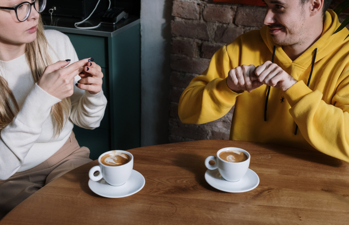 couple having coffee communicating with sign language