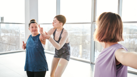 yoga instructor assisting teen girl