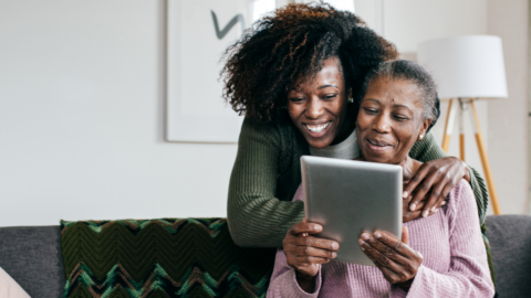 older adult female using ipad with young woman