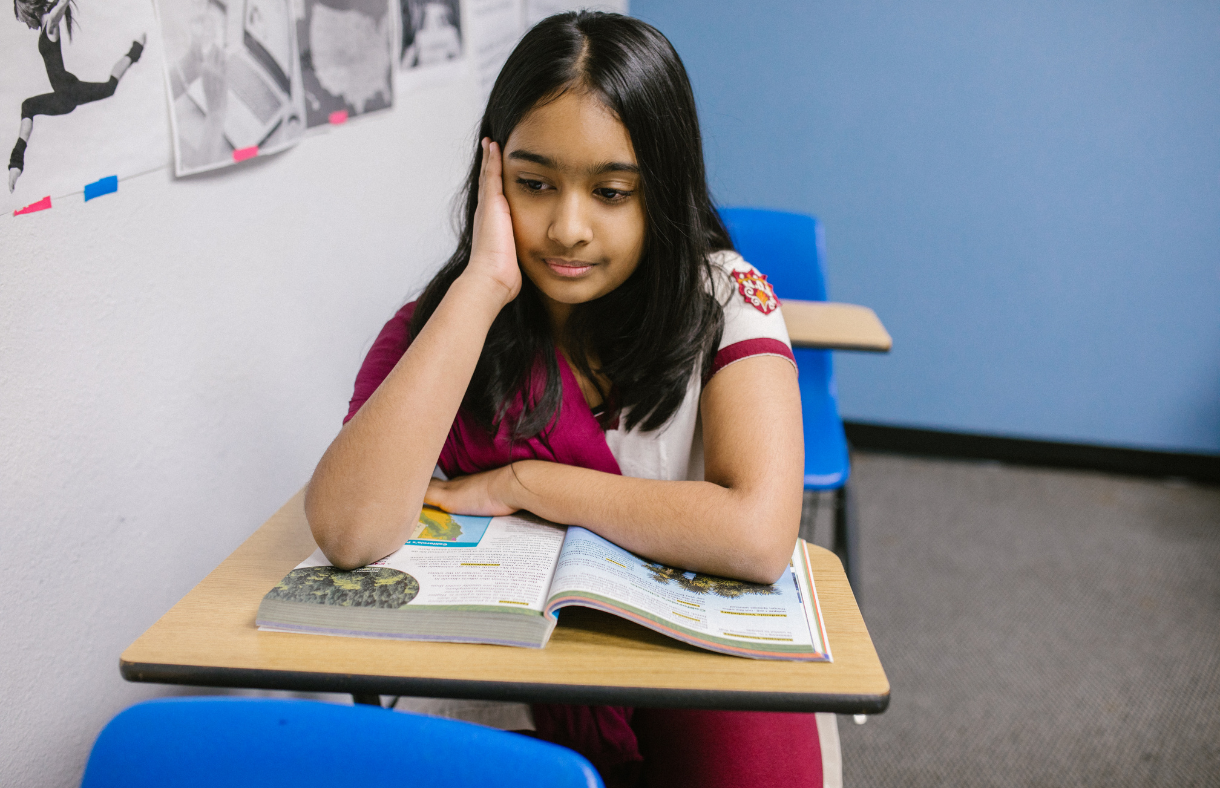 girl sitting at school desk looking frustrated