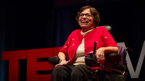 older adult female in wheelchair in front of TED talk sign