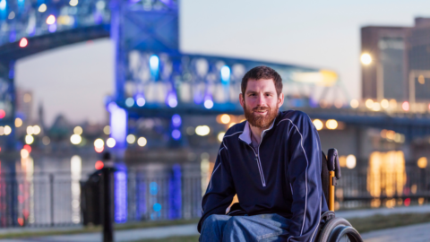 man in wheelchair outside in front of cityscape