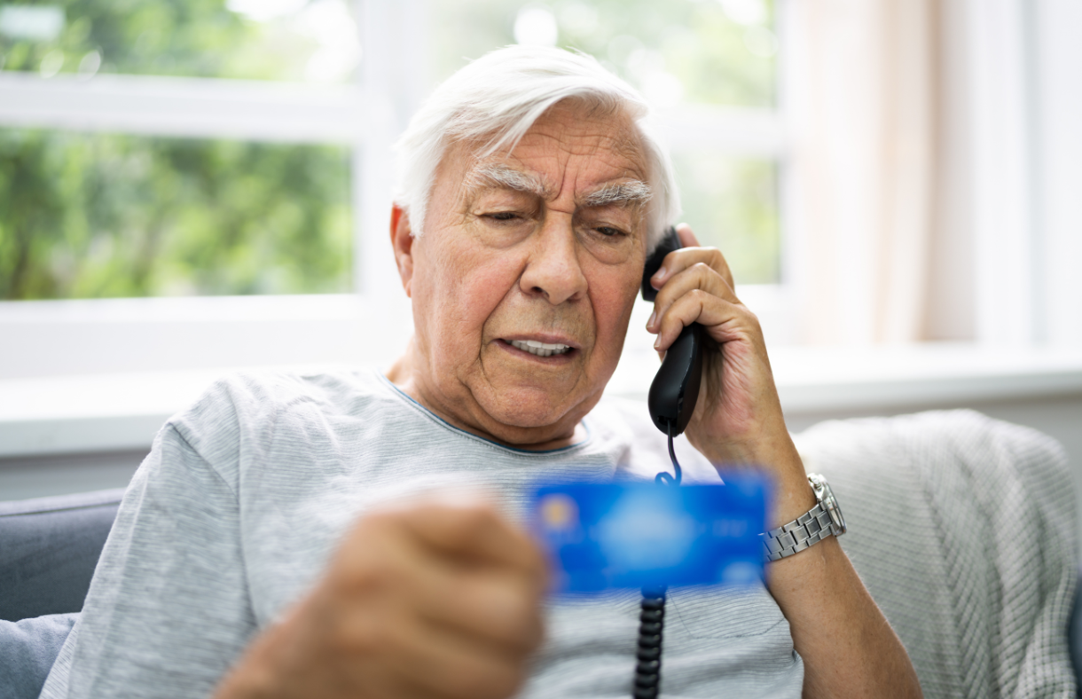 older adult man holding credit card while talking on the phone