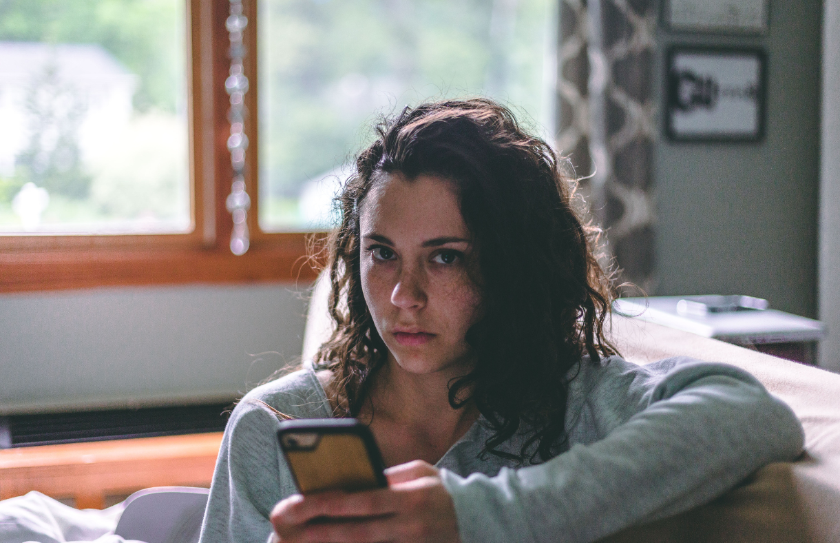 lady holding phone looking at camera