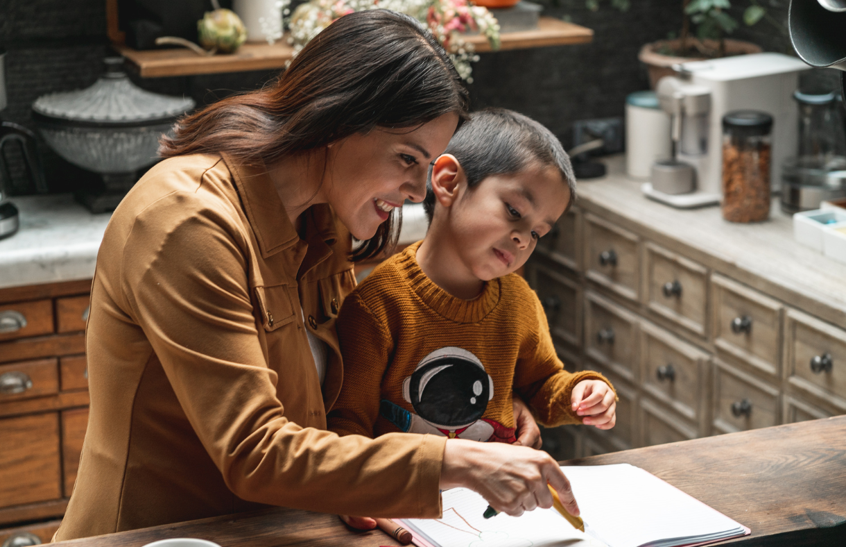 mom helping young son write in kitchen