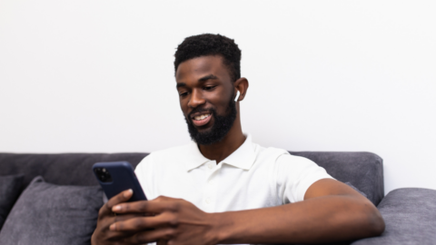 man looking at phone with airpods in ears