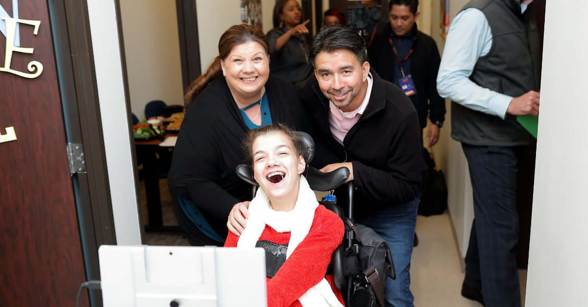 parents with teen girl in wheelchair using computer