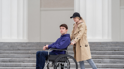 female pushing male in wheelchair outside