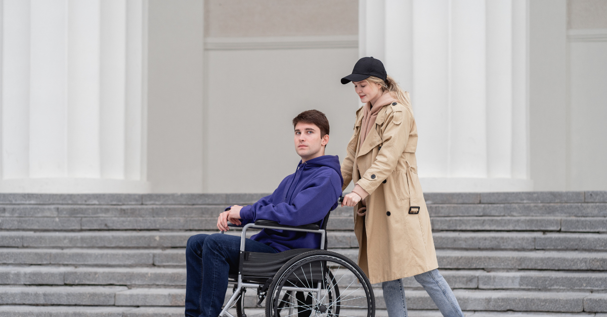 female pushing male in wheelchair outside