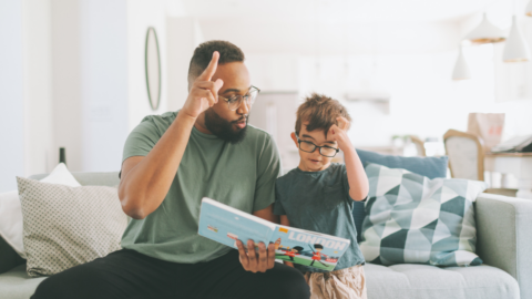 man and young boy looking at book together while using sign language