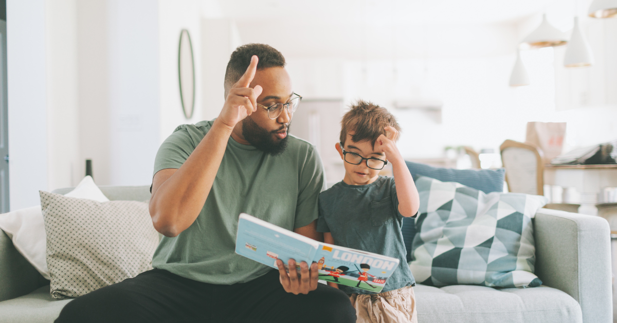 man and young boy looking at book together while using sign language