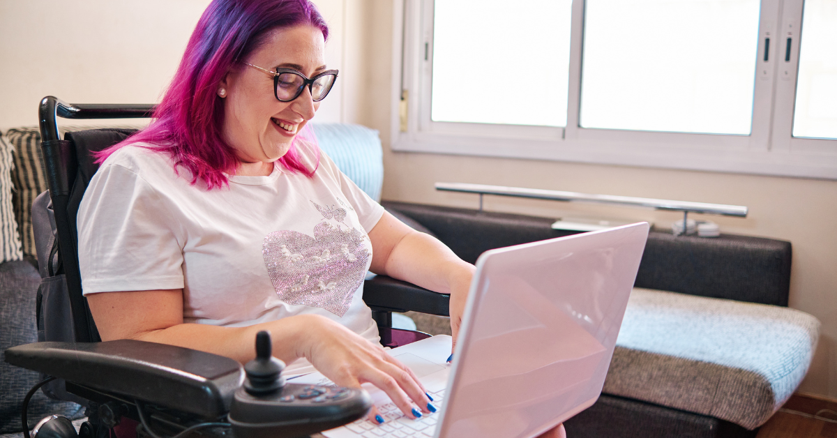 woman in wheelchair smiling at laptop screen