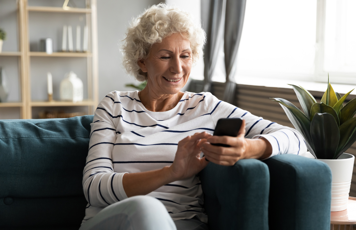 older adult woman using phone sitting on couch