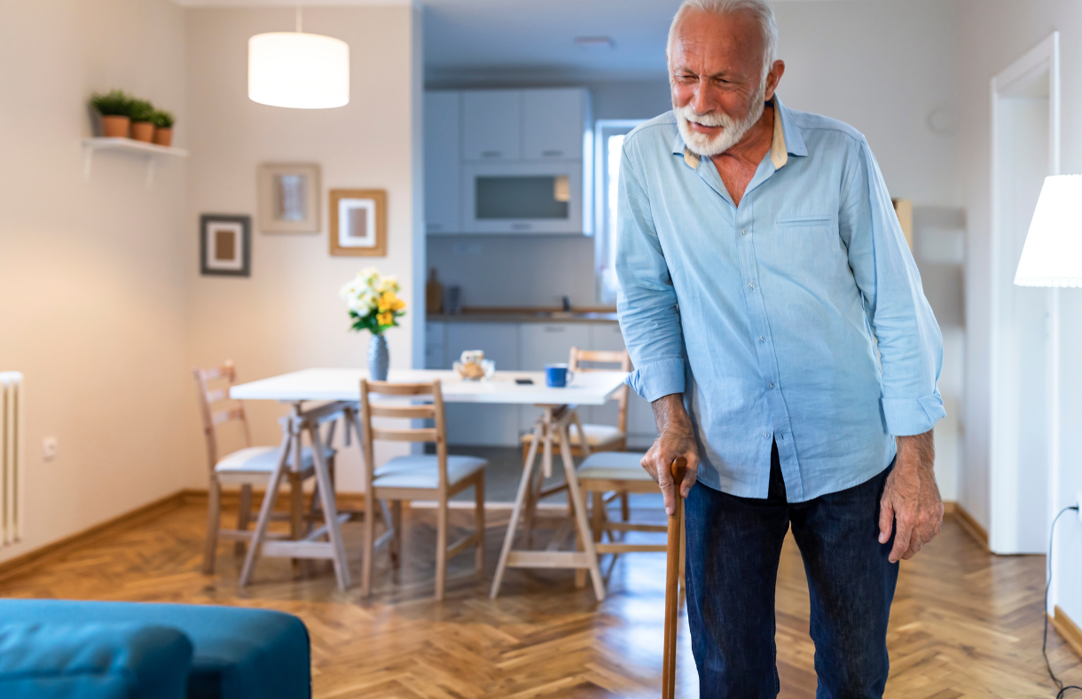 older adult man using cane to walk around house