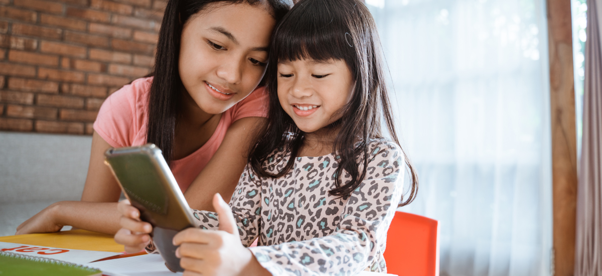 2 young girls in classroom looking at ebook together