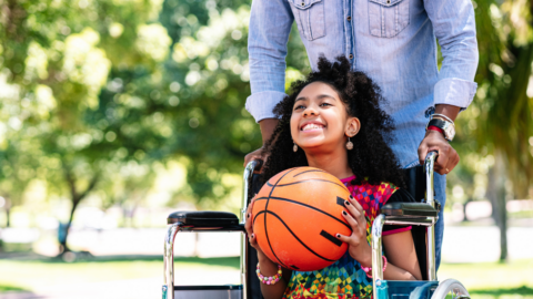 girl in wheelchair holding basketball