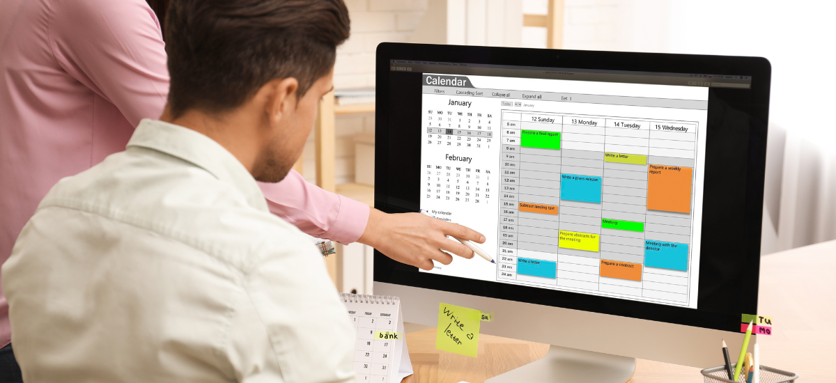 man looking at computer screen with calendar displayed