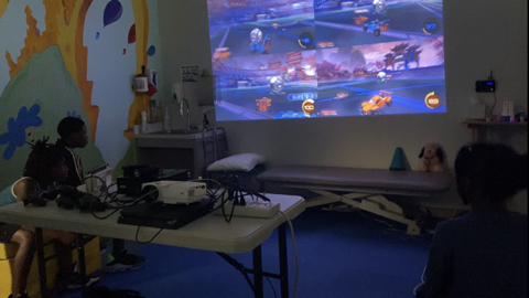 Three kids in front of giant video-game projection