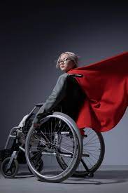 Teenager in wheelchair, wearing red cape that's flying out behind