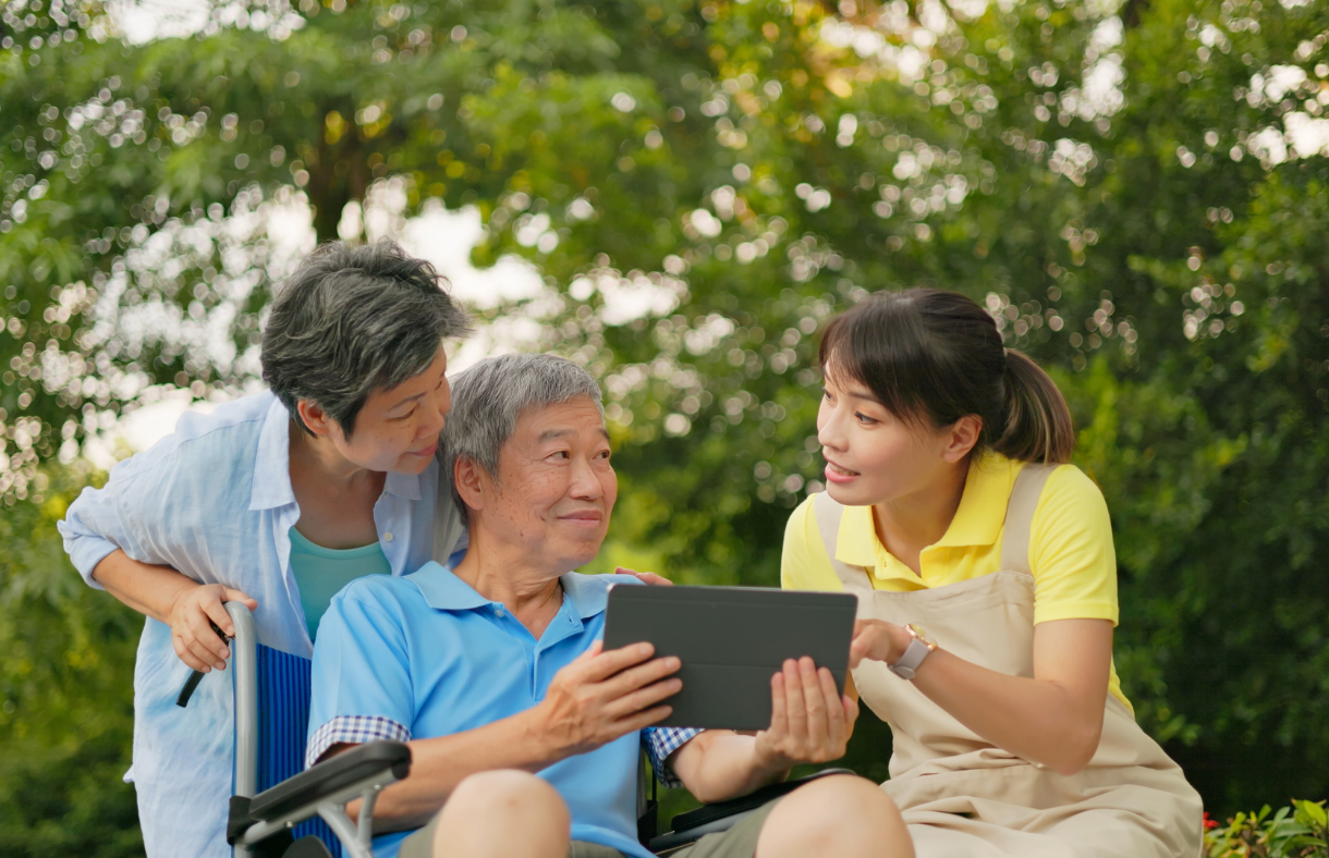 man using tablet being assisted by 2 women