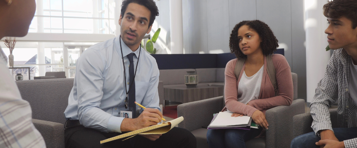 teen students meeting with adult teacher