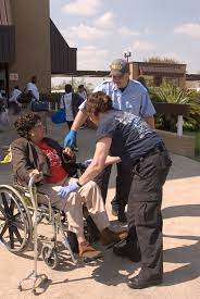 Outdoor setting: two emergency-services workers talking to person in wheelchair