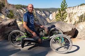 Man in wheelchair-style bike at nature-trail overlook.