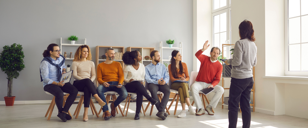 group of adults sitting in chairs in business office training