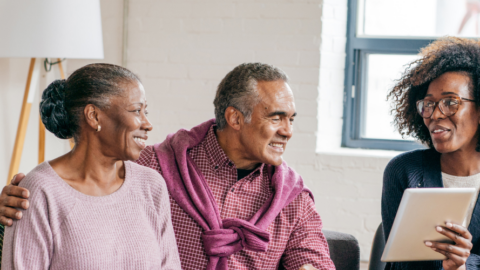 older man and woman sitting on couch talking with female provider