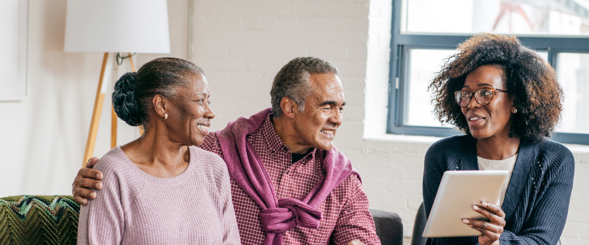 older man and woman sitting on couch talking with female provider
