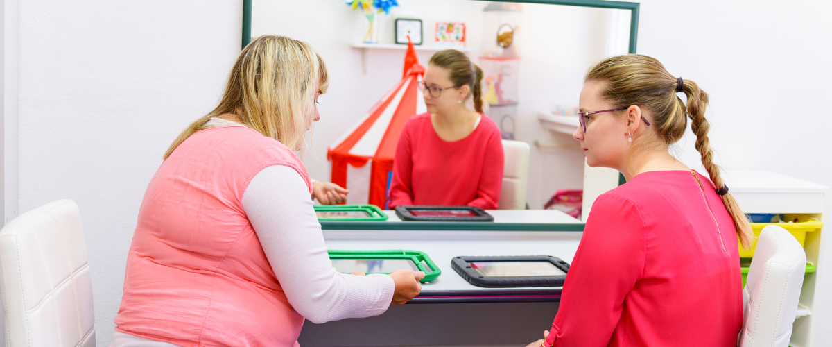 two females using ipad on table for augmentative communication