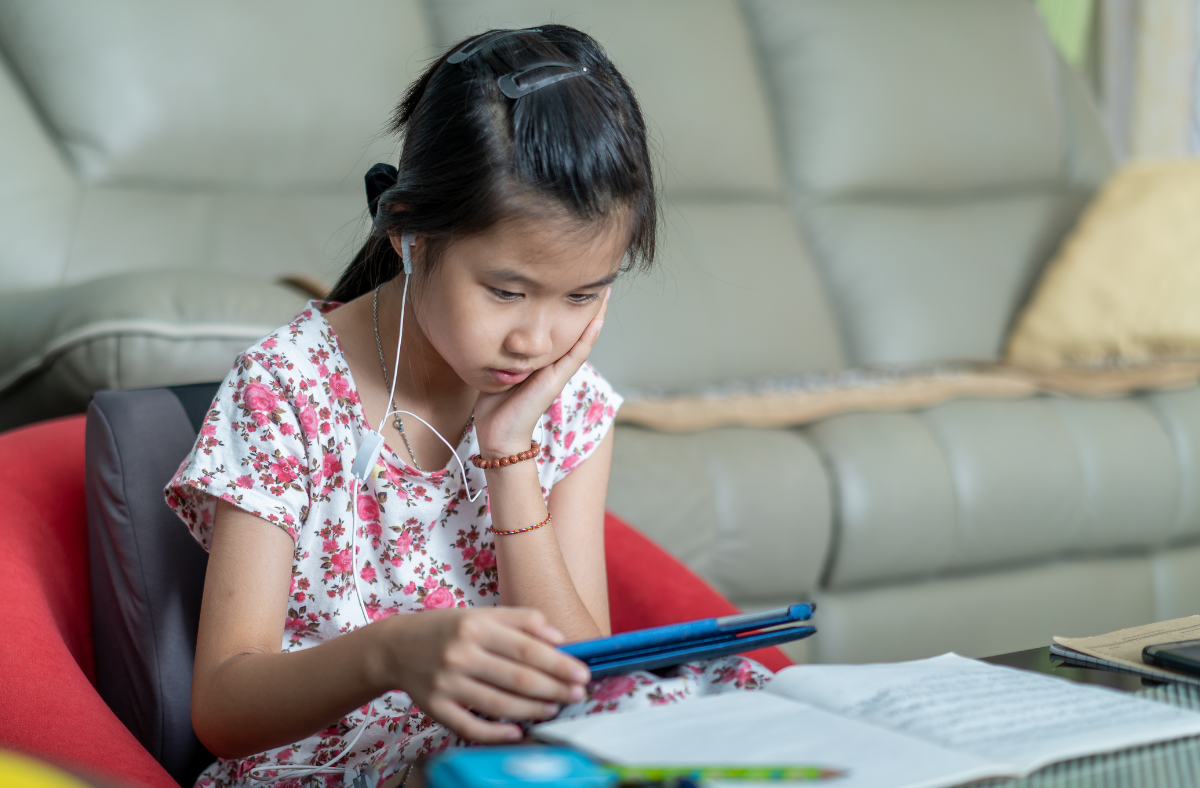 girl looking at ipad while doing homework