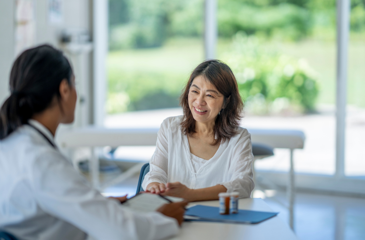 older adult woman sitting and chatting with female health care provider