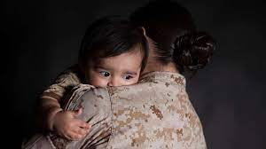 Child hugging mother in military uniform