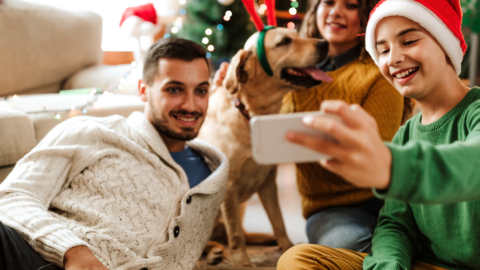 family in front of Christmas tree taking selfie