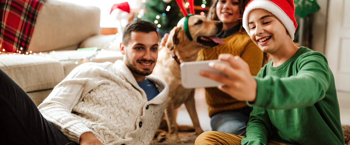 family in front of Christmas tree taking selfie